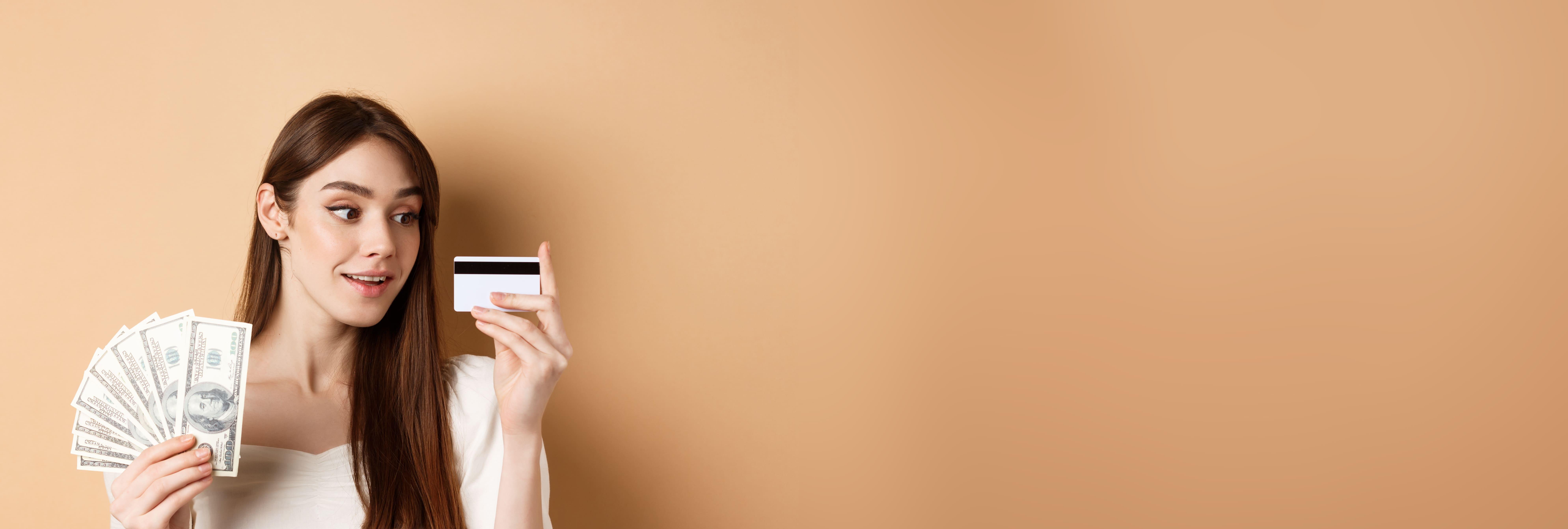 dreamy-girl-looking-plastic-credit-card-thinking-shopping-holding-dollar-bills-standing.jpg